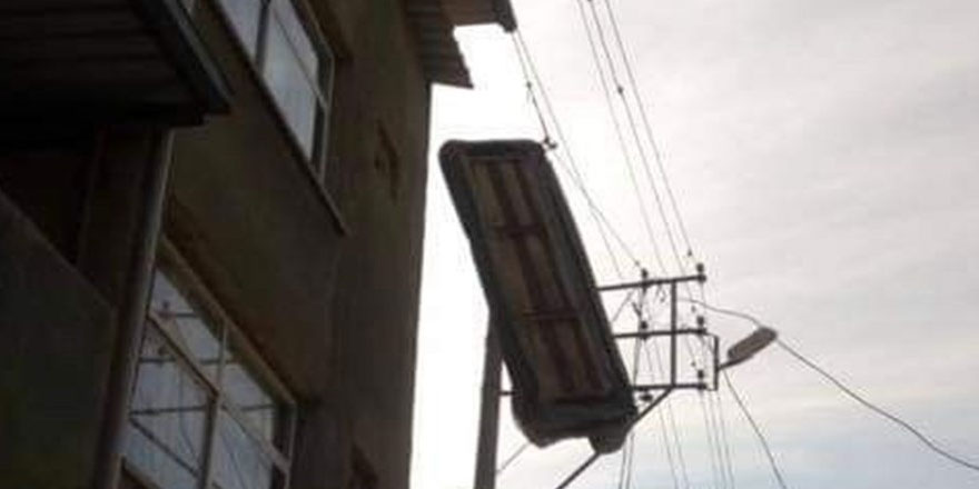 Çatı katından atılan üçlü koltuk, elektrik teline takıldı