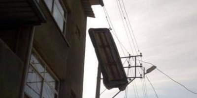 Çatı katından atılan üçlü koltuk, elektrik teline takıldı